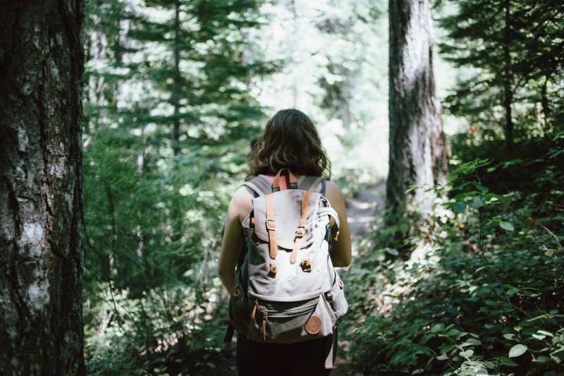woman in her backpack hiking in the middle of the forest